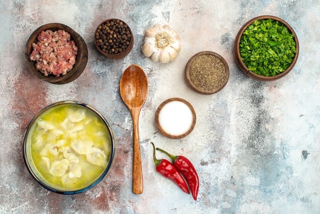 Vue de dessus bols de dushbara avec différentes épices verts viande cuillère en bois sur la surface nue place libre