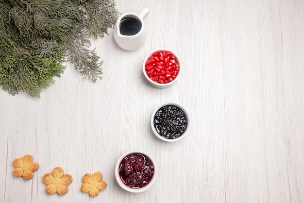 Vue de dessus des bols de grenade de biscuits à la confiture de grenade à côté des branches de l'arbre de Noël sur la table