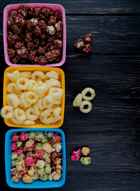 Vue De Dessus Des Bols De Pop-corn Comme Des Quilles Et Du Chocolat Avec Des Céréales Pop De Maïs Sur Une Surface En Bois Noire