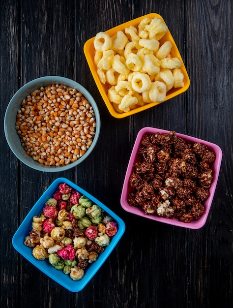 Photo gratuite vue de dessus des bols avec des quilles et des pop-corn au chocolat, céréales pop maïs et graines de maïs sur fond noir