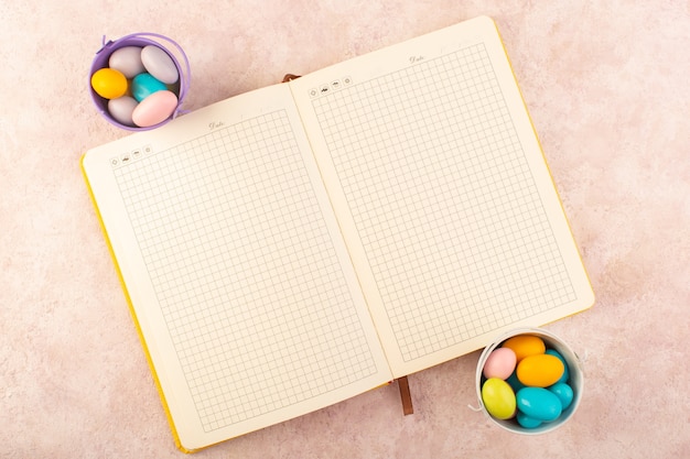 Une vue de dessus des bonbons colorés avec cahier sur le bureau rose bonbons de sucre sucré