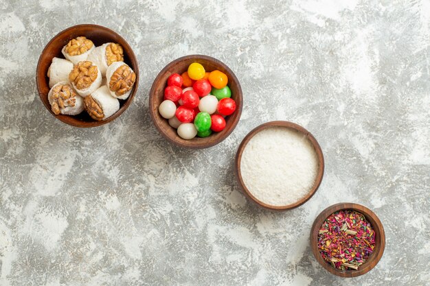 Vue de dessus des bonbons colorés avec des confitures de noix sur l'arc-en-ciel de bonbons couleur table blanche