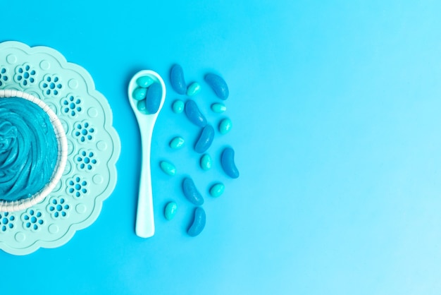 Une vue de dessus des bonbons colorés avec une cuillère blanche sur bleu