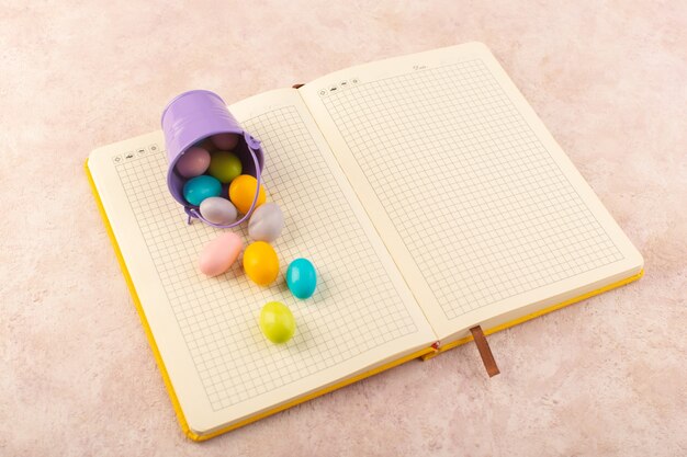 Une vue de dessus des bonbons colorés répartis sur tout le cahier et le bureau rose bonbons couleur sucre