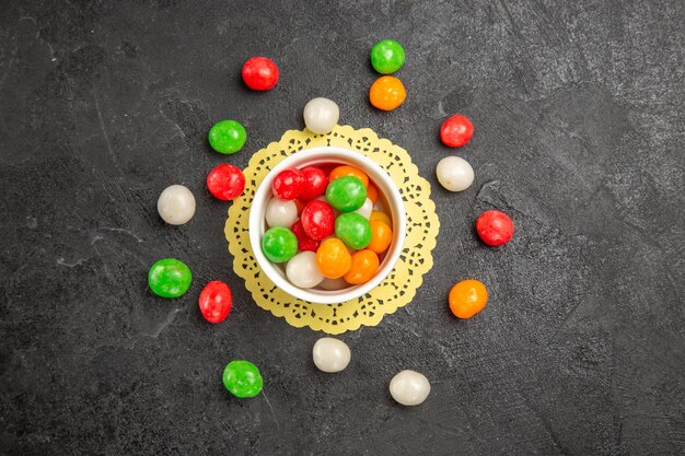 Vue de dessus des bonbons colorés sur le thé sucré arc-en-ciel de couleur de fond sombre