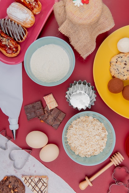 Photo gratuite vue de dessus des bonbons comme gâteau au chocolat avec des œufs de flocons d'avoine et de farine sur table rouge