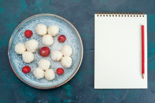 Vue de dessus des bonbons à la noix de coco et bloc-notes avec un crayon