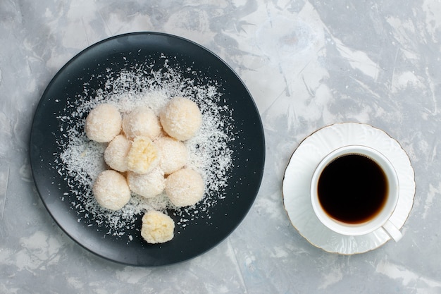 Vue de dessus des bonbons de noix de coco avec une tasse de thé sur blanc