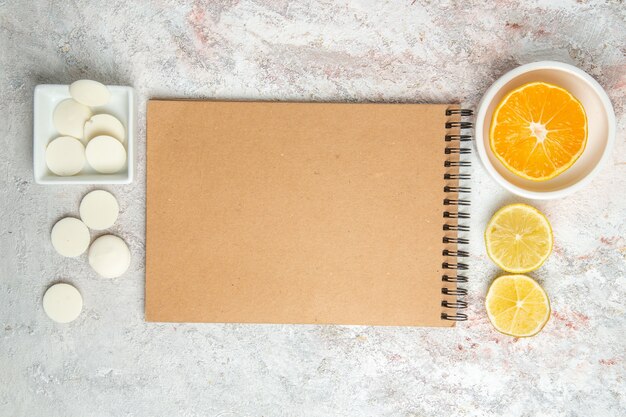 Vue de dessus des bonbons sucrés avec bloc-notes sur le biscuit de bonbons de table blanche