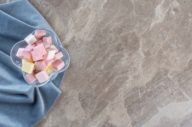 Photo gratuite vue de dessus de bonbons sucrés colorés dans un bol en verre sur une serviette.