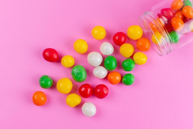 Une vue de dessus des bonbons sucrés colorés à l'intérieur et à l'extérieur peuvent sur rose, couleur sucrée de sucre