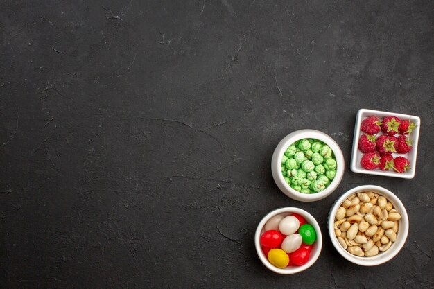 Vue de dessus des bonbons sucrés avec des noix sur une surface sombre du thé au sucre aux bonbons aux fruits sucrés