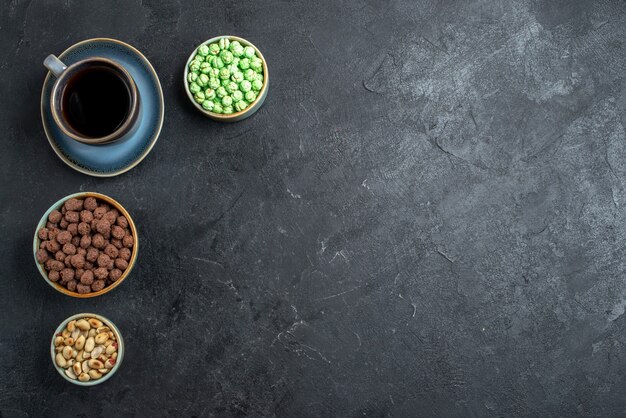 Vue de dessus des bonbons sucrés avec une tasse de café sur fond gris foncé