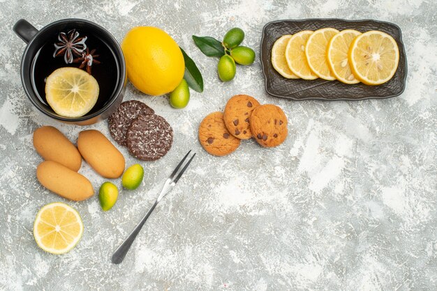 Vue de dessus des bonbons une tasse de thé avec des biscuits au citron fourchette de citron en tranches d'agrumes