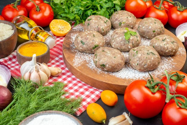 Vue de dessus des boulettes de viande sur une planche brune et de la farine de riz citron vert frais bouteille d'huile tombée légumes frais gingembre jaune sur une serviette dépouillée rouge sur fond noir