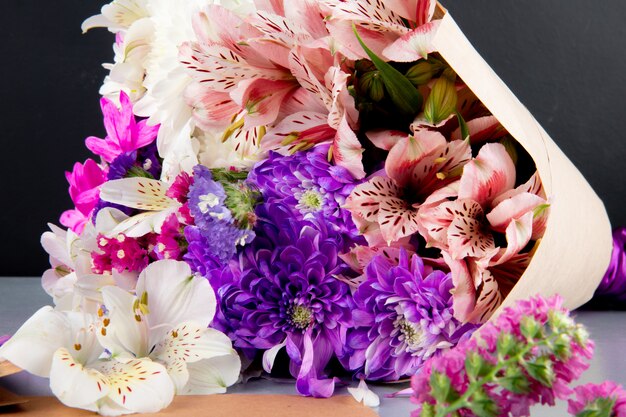 Vue de dessus d'un bouquet d'alstroemeria de couleur blanche et rose et de fleurs de chrysanthème en papier kraft sur fond sombre