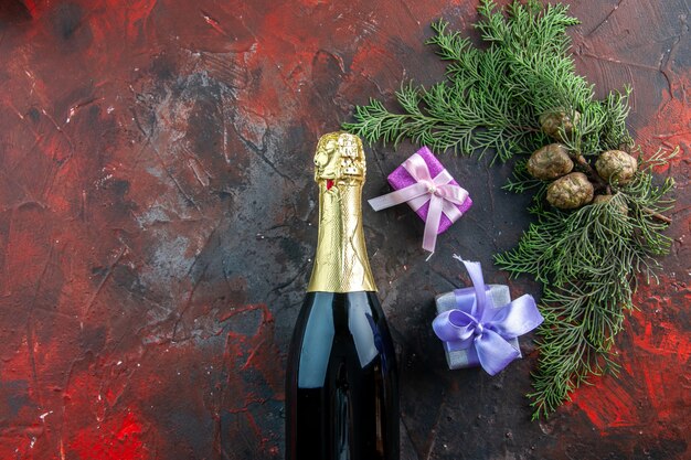Vue de dessus d'une bouteille de champagne avec des cadeaux sur une boisson de couleur sombre alcool photo fête du nouvel an