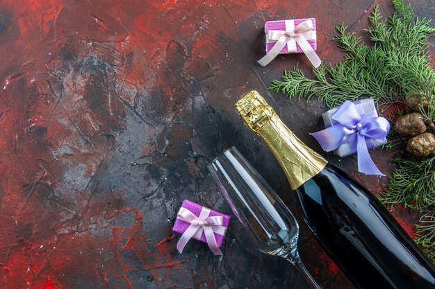Vue de dessus d'une bouteille de champagne avec de petits cadeaux sur une boisson de couleur sombre alcool photo fête du nouvel an