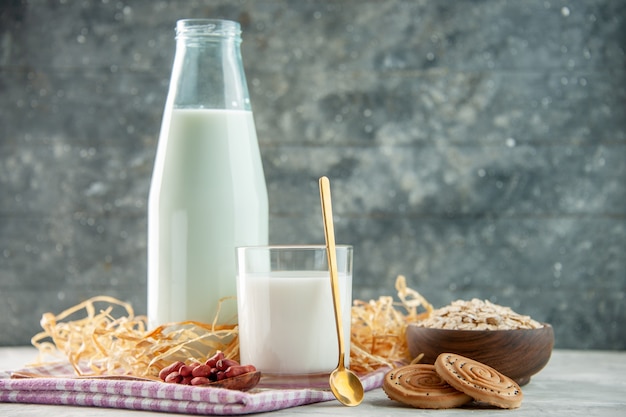 Vue de dessus d'une bouteille en verre ouverte remplie de lait et de haricots dans des biscuits à la cuillère d'avoine sur une serviette dénudée violette