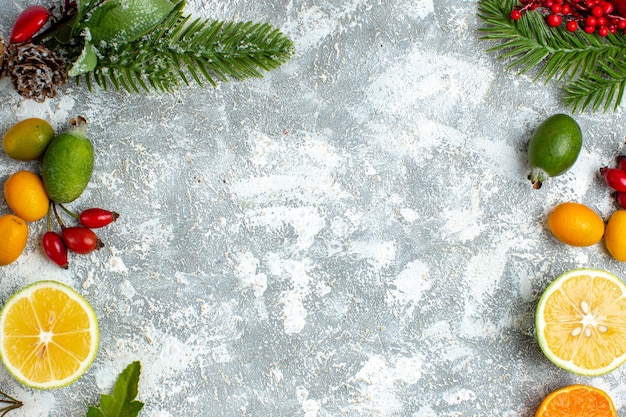 Photo gratuite vue de dessus des branches d'arbres de noël coupés des citrons feijoas sur un espace libre de table grise