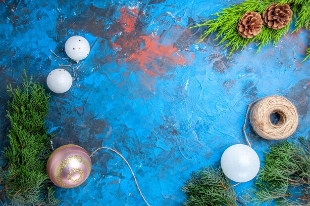 Vue de dessus des branches de pin cônes fil de paille boules d'arbre de Noël sur une surface bleu-rouge