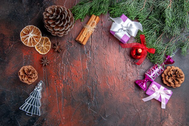 Vue de dessus des branches de pin avec des cônes jouets d'arbre de Noël tranches de citron séchées à la cannelle anis étoilés sur fond rouge foncé espace libre photo du nouvel an