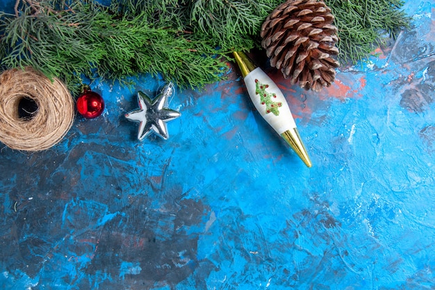 Vue de dessus des branches de pin avec fil de paille de pomme de pin sur une surface bleu-rouge