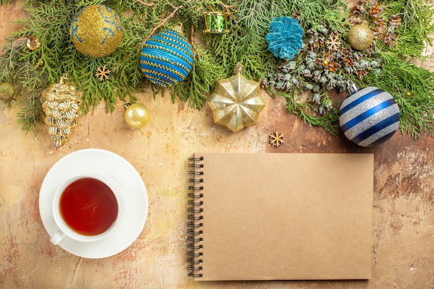 Vue de dessus des branches de sapin ornements d'arbre de Noël une tasse de cahier de thé sur fond beige