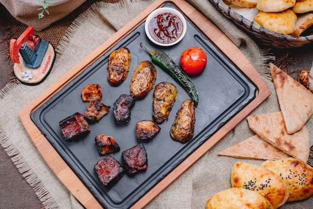 Photo gratuite vue de dessus brochette de foie de boeuf avec pommes de terre et tomates au poivron vert grillé et sauce sur un plateau