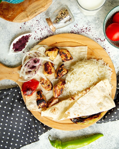 Vue de dessus de brochette de poulet servi avec riz oignon plat et sumac