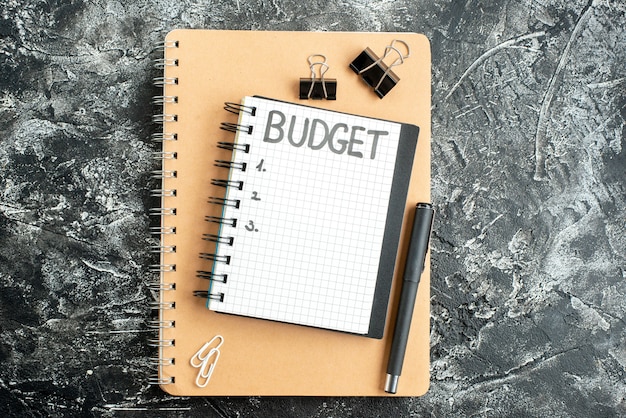 Vue de dessus budget écrit note sur le bloc-notes avec un stylo sur la surface sombre étudiant cahier couleur argent école gris business