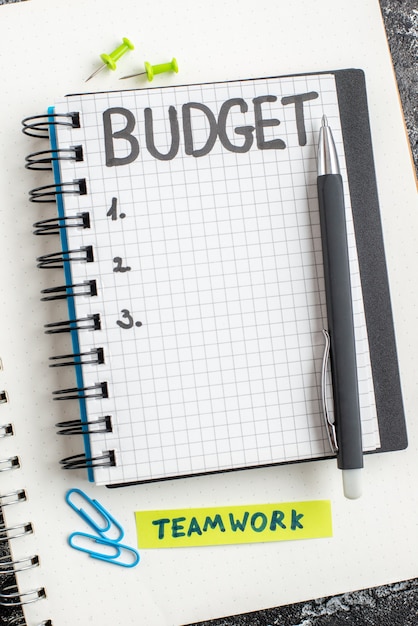 Vue de dessus budget note écrite sur le bloc-notes avec un stylo sur la surface sombre étudiant cahier couleur argent gris college business