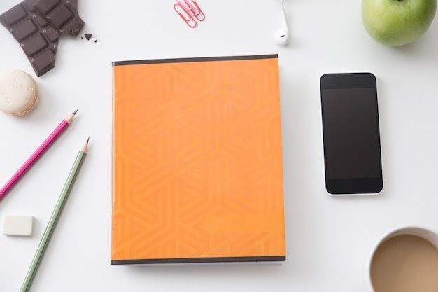 Vue de dessus d&#39;un bureau avec un cahier orange