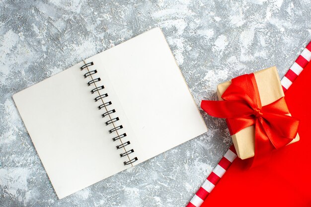 Vue de dessus cadeau de Noël attaché avec un cahier à ruban rouge sur une table blanche grise