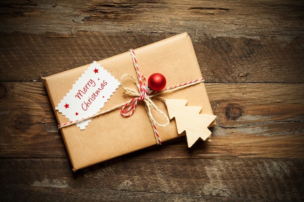 Vue de dessus d'un cadeau de Noël emballé avec une carte qui lit Joyeux Noël, sur une surface en bois