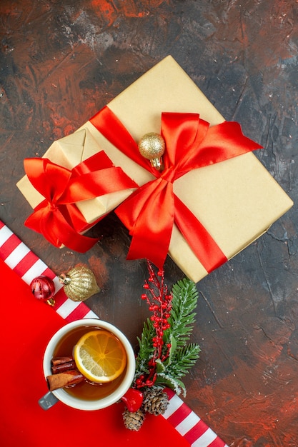 Vue de dessus des cadeaux de Noël attachés avec une branche d'arbre de Noël en ruban rouge sur une table rouge foncé