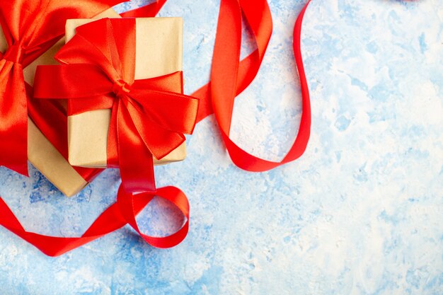 Vue de dessus des cadeaux de Noël attachés avec un ruban rouge sur un espace libre de table bleu blanc