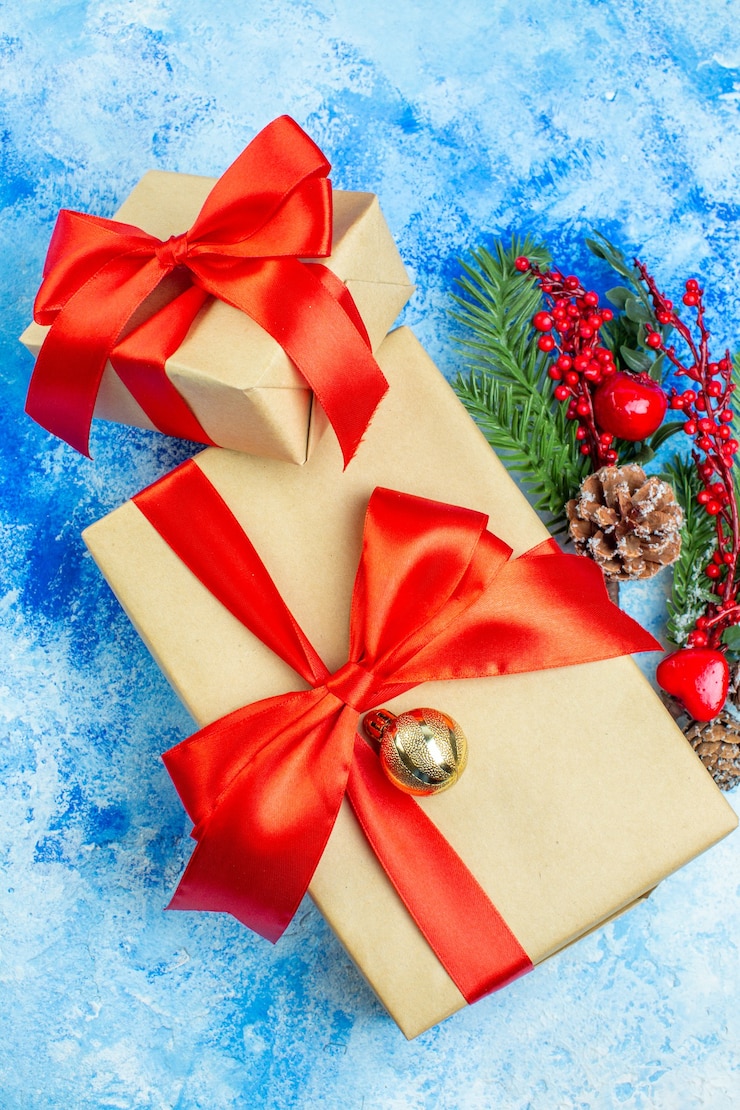 Photo gratuit vue de dessus des cadeaux de vacances attachés avec des ornements de noël en ruban rouge sur un tableau blanc bleu