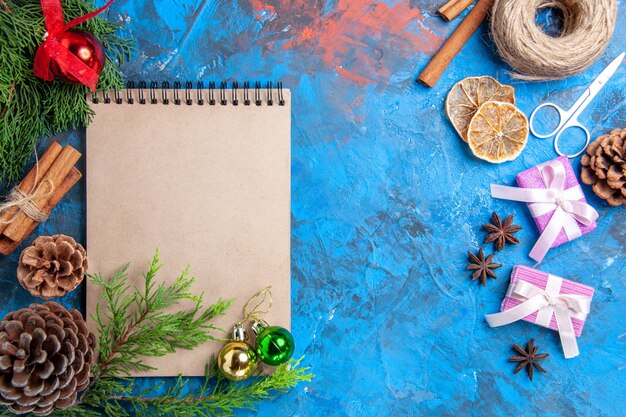 Vue de dessus un cahier branches de pin pomme de pin étoile anis ciseaux fil de paille sur fond bleu espace libre