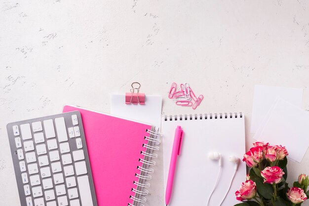 Vue de dessus des cahiers sur le bureau avec bouquet de roses et espace copie