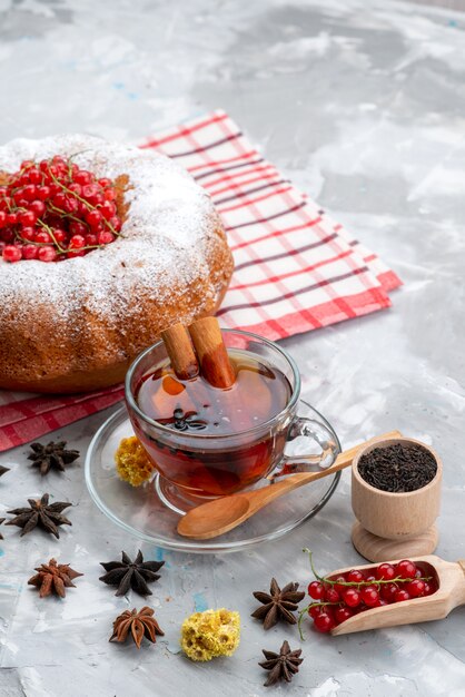 Une vue de dessus de canneberges rouges fraîches aigre-doux et moelleux avec du thé gâteau rond et de la cannelle sur le bureau blanc couleur fraîche