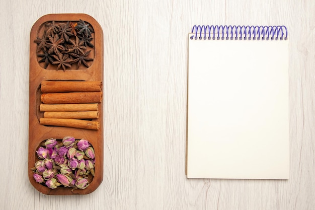 Vue de dessus de la cannelle fraîche avec des fleurs sur du bois de couleur plante fleur de bureau blanc