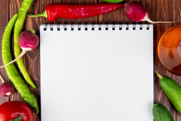 Vue de dessus d'un carnet de croquis et de légumes piments, radis et concombres sur bois rustique