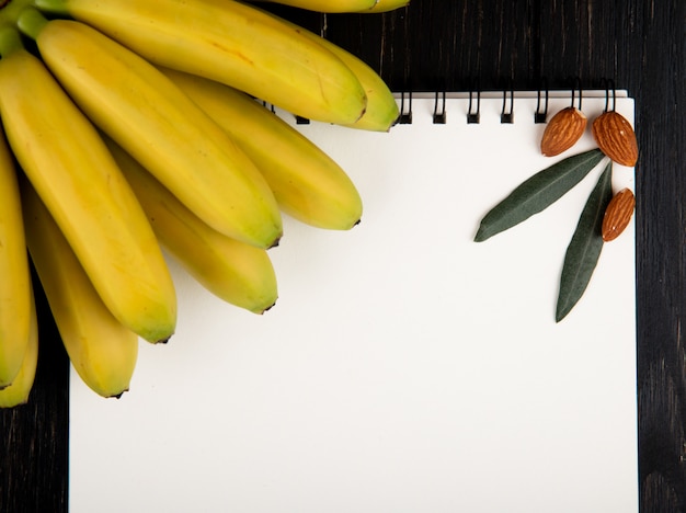 Photo gratuite vue de dessus d'un carnet de croquis et de nouvelles bananes aux amandes sur fond noir