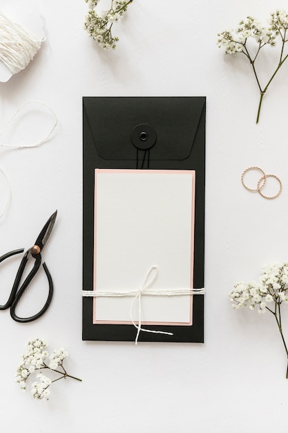 Une vue de dessus de cartes de vœux avec des ciseaux; anneaux de mariage; ficelle et fleur sur fond blanc