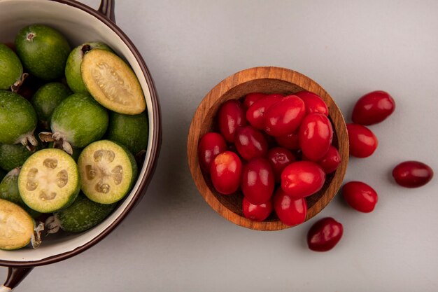 Vue de dessus de cerises de cornaline fraîches sur un bol en bois avec feijoas sur un bol sur un mur gris