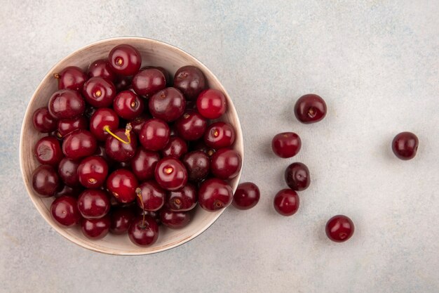 Vue de dessus des cerises dans un bol et sur fond blanc