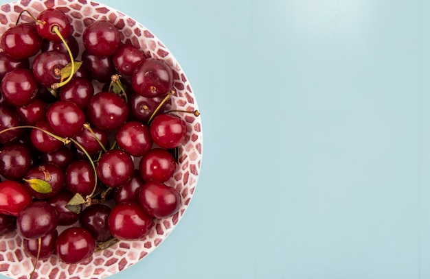 Vue de dessus des cerises dans un bol sur fond bleu avec espace copie