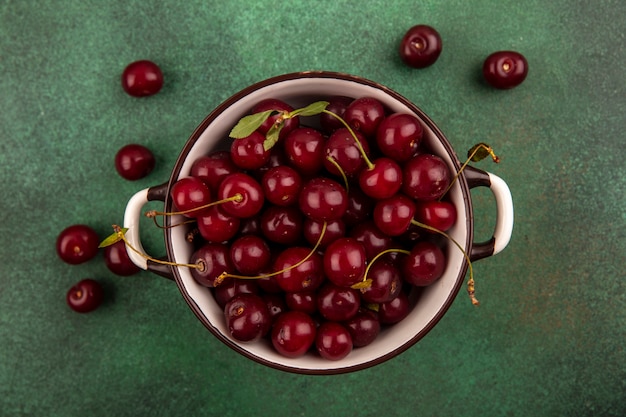 Vue de dessus des cerises dans un bol et sur fond vert