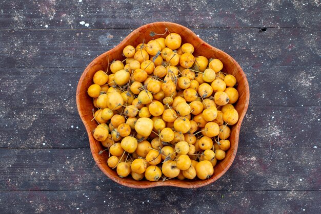 Vue de dessus cerises jaunes sucrées moelleuses et juteuses à l'intérieur de la plaque sur le fond gris fruit cerise douce fraîche